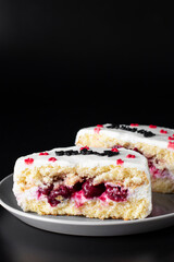 Sliced bento cake with cherry filling on plate on a black background