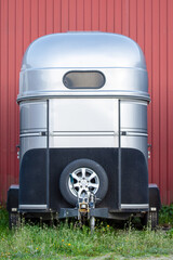 Modern metal horse trailer with spare wheel on the green grass