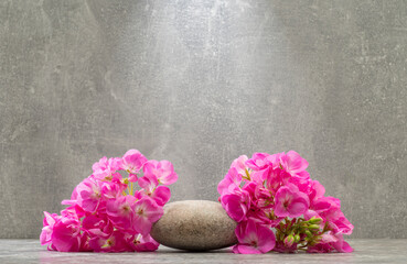 Obraz na płótnie Canvas gray zen stones and pink flowers on a gray background for product presentation podium background