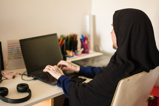 Trans muslim person using laptop at home
