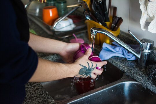 Person with tattoos doing the dishes