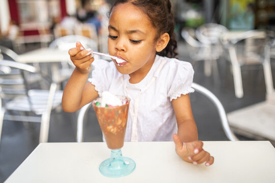 small girl eating ice cream enthusiastically outdoors