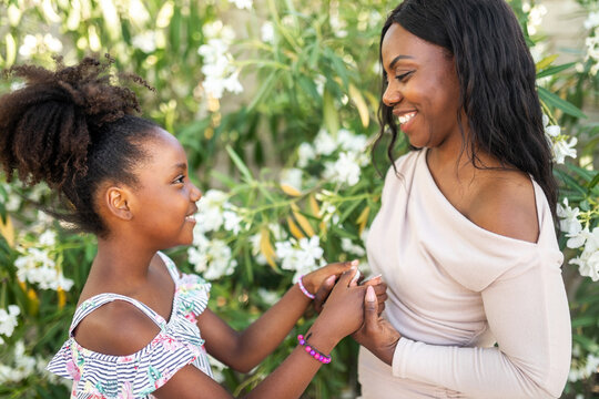 black mother with her daughter surrounded by white flowers