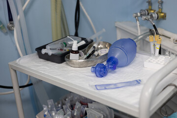 In the operating room, there is a resuscitation kit on the table. An ambu oxygen bag lies on a table with medicines in a veterinary surgery. Resuscitation kit for an emergency in surgery.