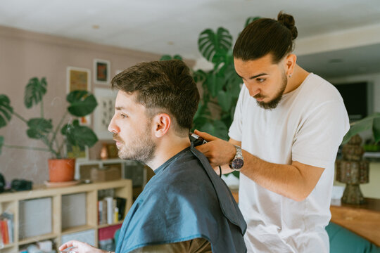 Skillful barber giving a haircut at home