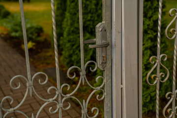 Artsy grey metal fence with a lock on a property entrance