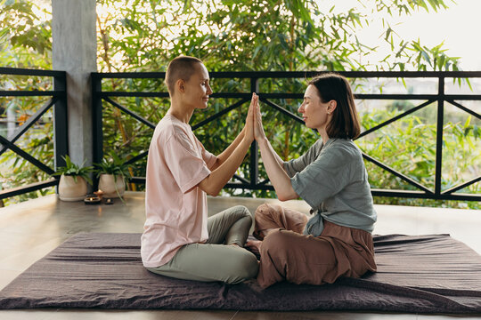 Calm women clasping hands together on mat