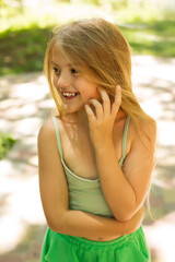 beautiful happy long-haired blonde girl in a green suit made of natural fabric on the street