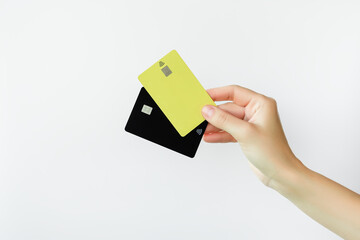 female hand holds two plastic bank cards on a white background