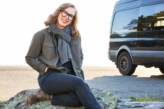 Portrait Of Happy Mature Woman By Her Camper Van On Road Trip