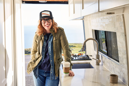 Portrait of woman in camper van in nature with coffee on road trip