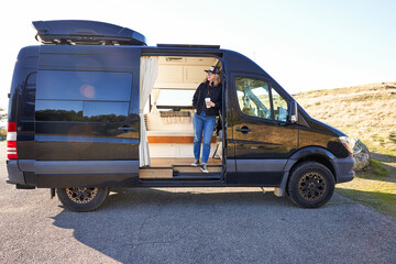 Portrait of woman with coffee in camper van in nature