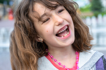 Toothless happy smile of a girl with a fallen lower milk tooth close-up. Changing teeth to molars...
