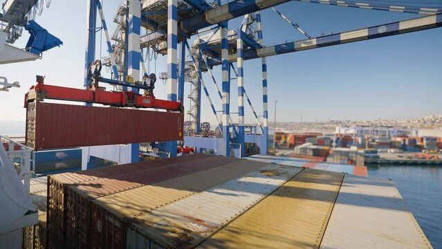 4K scene of port crane lifting red container from docked ship stock video. 