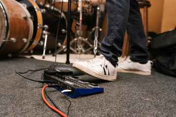 Crop guitarist pushing effects unit during rehearsal