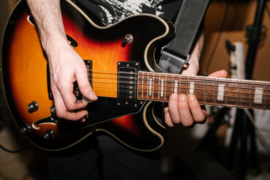 Crop rocker playing electric guitar in studio
