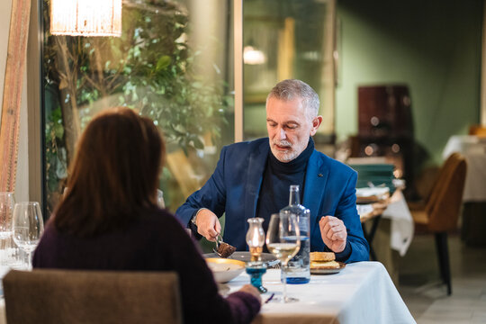 Calm senior man having dinner with wife in restaurant