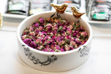 Beautiful plate with dry rosebuds for tea. A large pile of dried roses is used as an addition to tea for flavor. Element of the tea ceremony in the form of an additive of roses close-up
