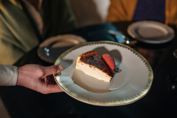 Crop waiter serving dessert to guest