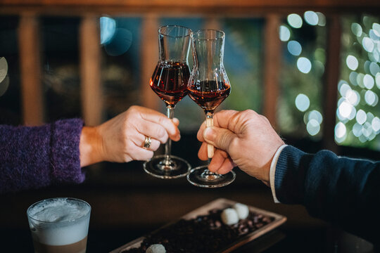 Crop couple clanging glasses of wine while celebrating in restaurant