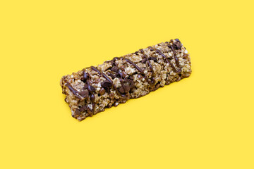 Muesli chocolate bar on a yellow background. Healthy sweet dessert snack. Cereal muesli with nuts, chocolate and berries on a yellow background. Carbohydrate bar for energy replenishment