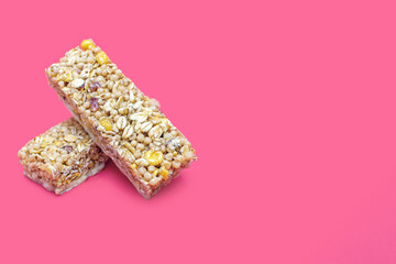 Two muesli bars on a pink background with free space for text. Healthy sweet dessert snack. Cereal muesli with nuts, oatmeal and berries on a yellow background. Delicious and healthy dessert