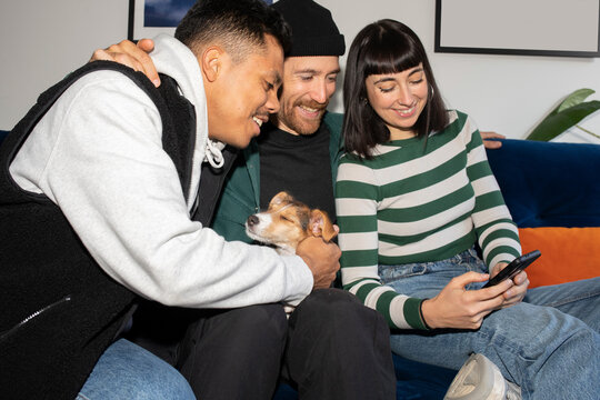 Friends laughing while using smartphone in a sofa