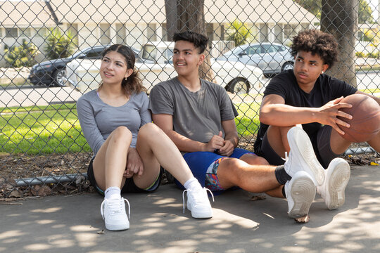 Friends sitting together against a chain fence 