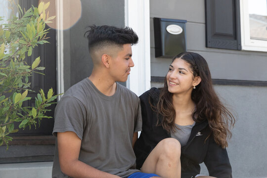 Teen couple being sweet together outside a suburban home 