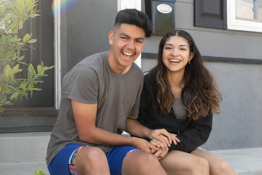 Teen couple being sweet together outside a suburban home 