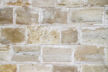 An old beige stone wall made of gang-sawn sandstone as a background