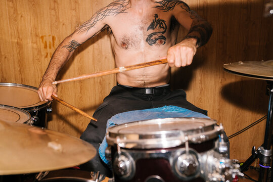 Crop tattooed drummer playing drums
