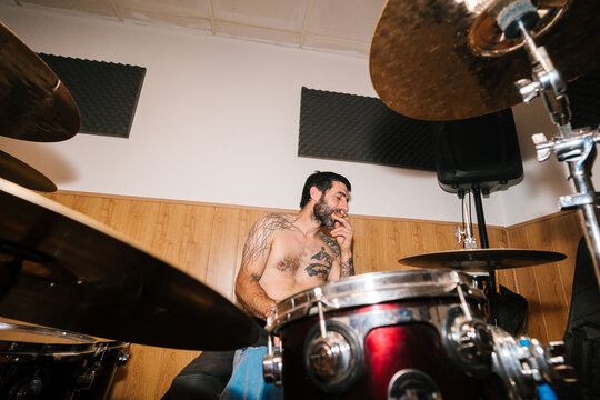Bearded drummer smoking while playing drums