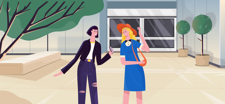 Two stylish modern female friends engaging in conversation in the city