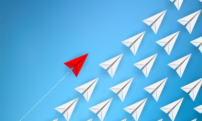 A red paper plane flies alongside a swarm of white paper planes in an attempt to illustrate difference and distinction from others. Copy space
