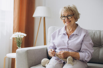 Elderly woman knitting at home. Creative hobby