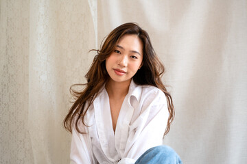 Asian woman posing on fabric backdrop.