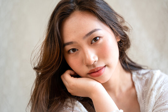 Asian woman posing on fabric backdrop.