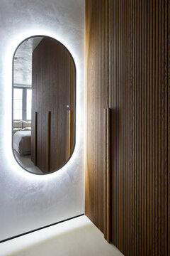 Closet with round mirror backlighted reflecting the bed and wardrobe 