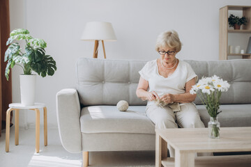 Elderly woman knitting at home. Creative hobby
