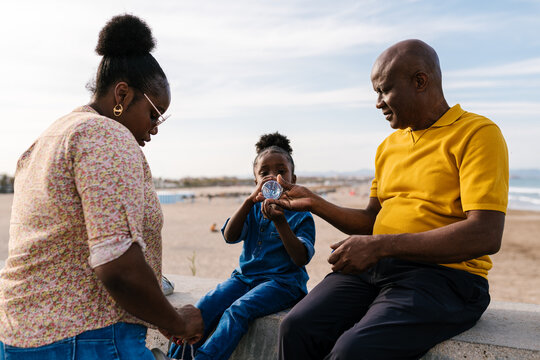 Black father giving water to child