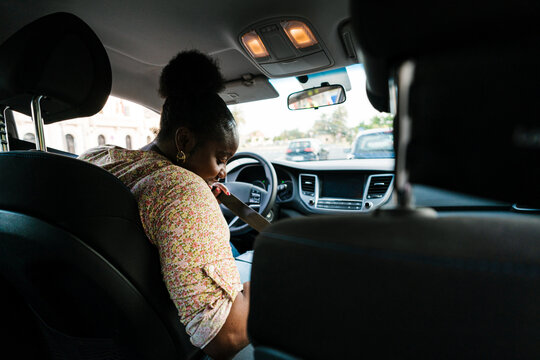 Focused black woman fastening seat belt in car