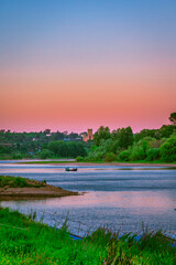 Naklejka premium Fishermen´s boat in the Tagus river at sunset, with the templar castle of Almourol on the background, in the portuguese village of Arripiado - Chamusca - Portugal