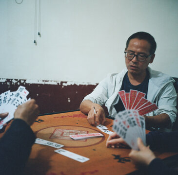 Three people are playing a Chinese poker called "Pao Huzi"
