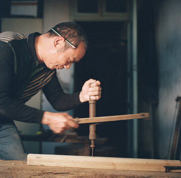 The carpenter is using tools to drill holes
