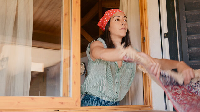 Woman shaking the rug out the window
