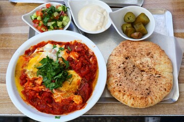 Israeli cuisine. Shakshuka lunch - poached eggs in spicy pan fried tomatoes.