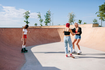 Young blonde latin Teen girl learning to skate with her friends