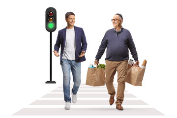 Young man and mature man with grocery bags walking at a pedestrian crosswalk and talking
