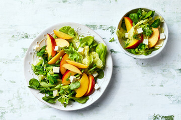 Summer nectarine salad with green leaf vegetables and feta. Top view - 620712247